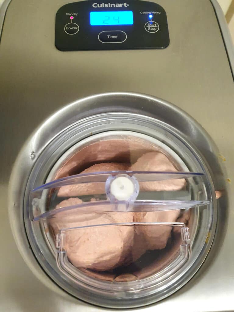 Top down view of strawberry ice cream churning in ice cream machine.