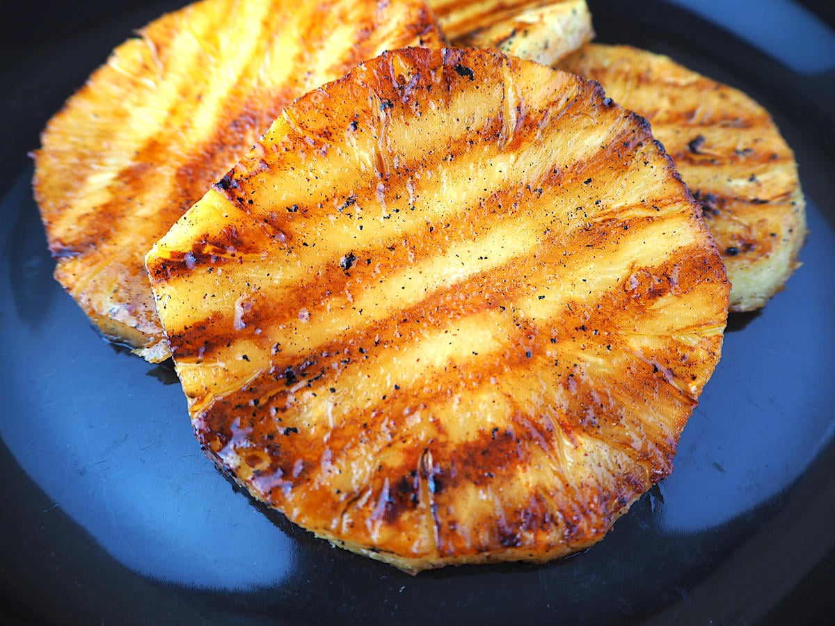 close up grilled pineapple showing griddle line on black plate.
