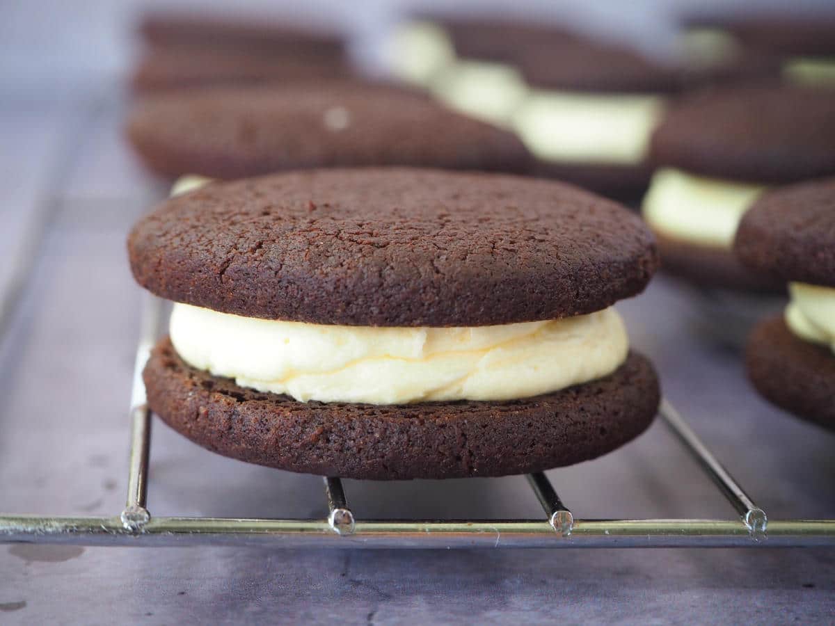 close up side view of homemade oreos on wire rack.