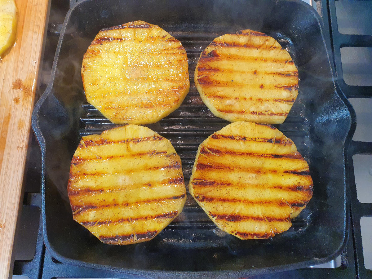 pineapple cooking in griddle pan showing cooked side of pineapple with griddle lines.