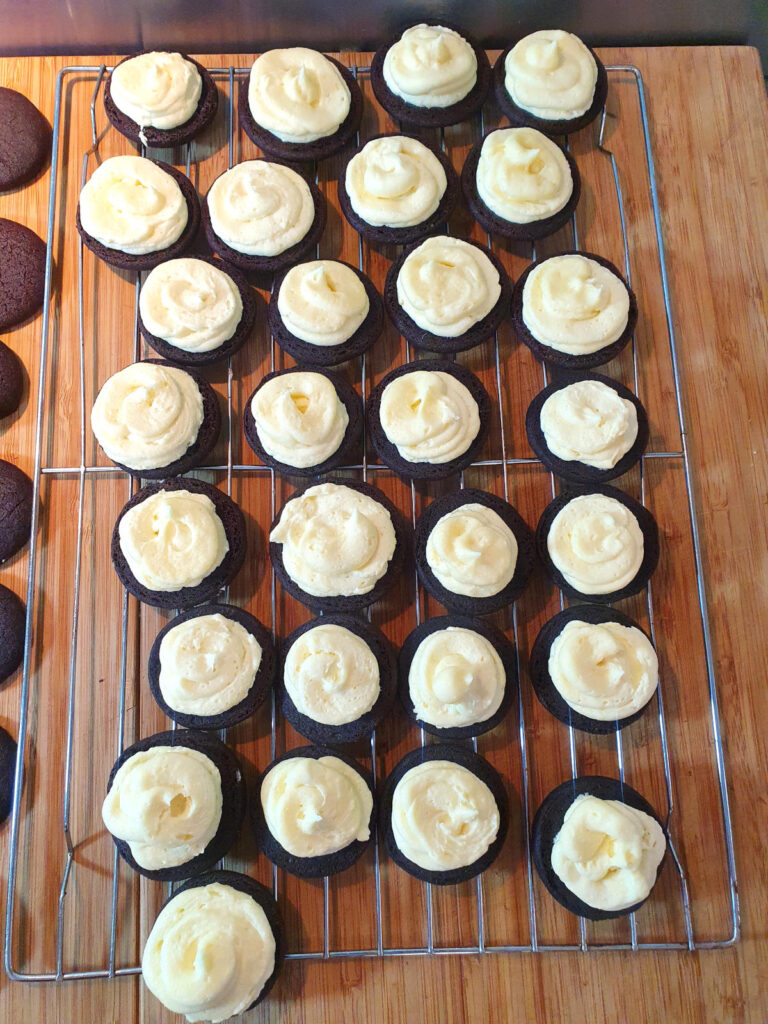 top down view cookies with vanilla filling on a wire rack, ready for cookies to place on top.