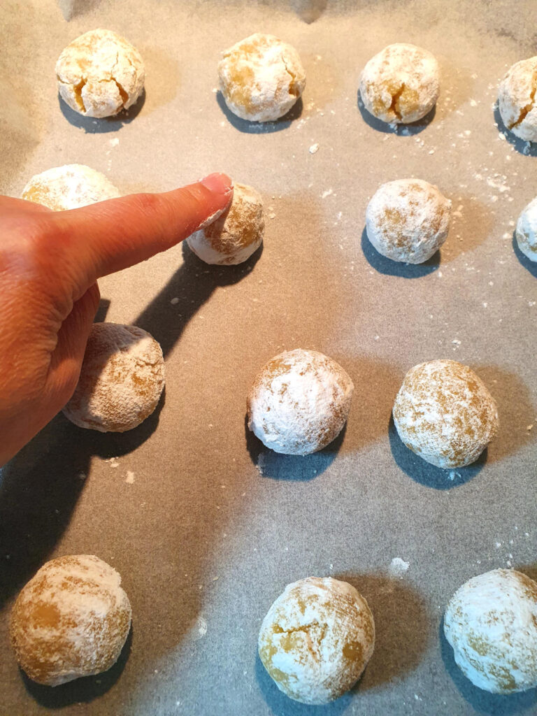 Amaretti cookies 14 lightly pressing down cookies on lined baking tray with a single finger.