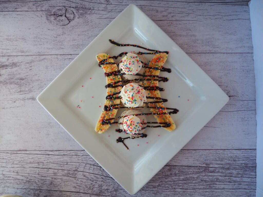 Banana split 9 top downview of making banana split, adding coloured sprinkles.