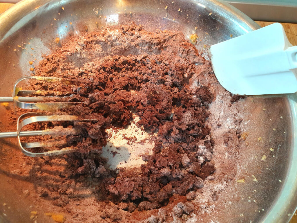 mixing dry ingredients for oreo cookies with beaters to the left and white spatular to the right to scrap down bowl.