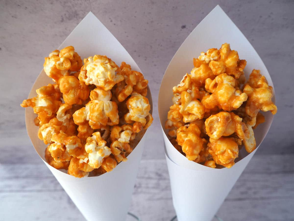 Two white paper cones of caramel popcorn.