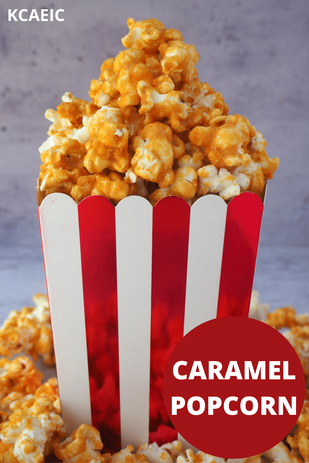 Caramel popcorn pilled in a red and white striped box, with caramel popcorn scattered around the bottom and text overlay, caramel popcorn and KCAEIC.