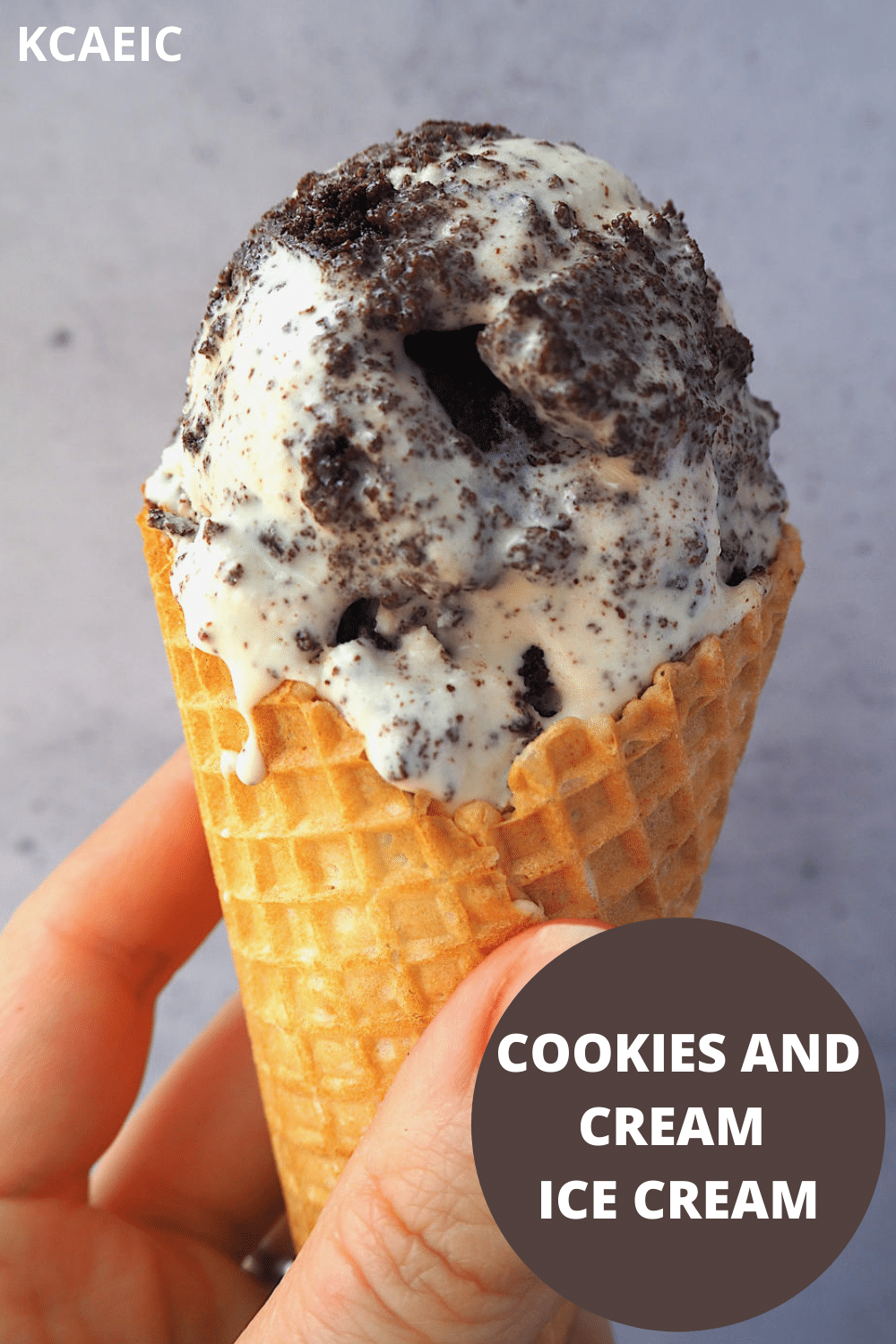 Close up of scoop of cookies and cream ice cream in a waffle cone being held, with text overlay, cookies and cream ice cream, KCAEIC.