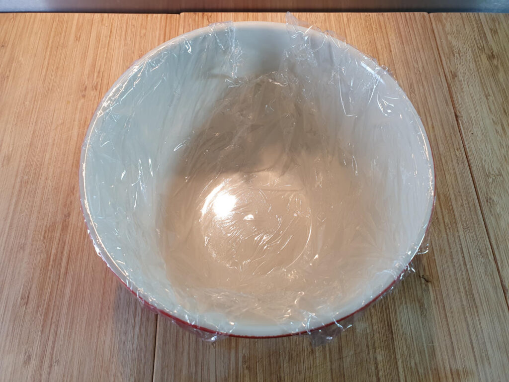 Lining pudding bowl with first layer of cling film.