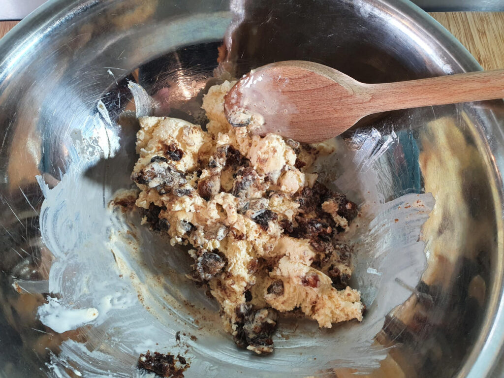 Starting to mix vanilla ice cream, Christmas pudding and brandy together in a large mixing bowl with a big wooded spoon.