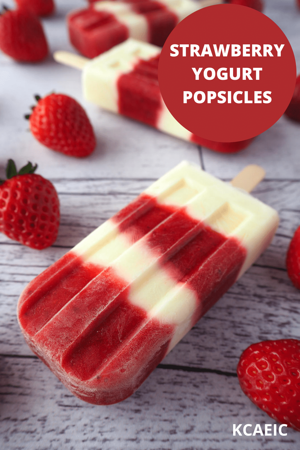 Close up strawberry yogurt popsicles on a diagonal surrounded by fresh strawberries with text overlay, strawberry yogurt popsicles, KCAEIC.