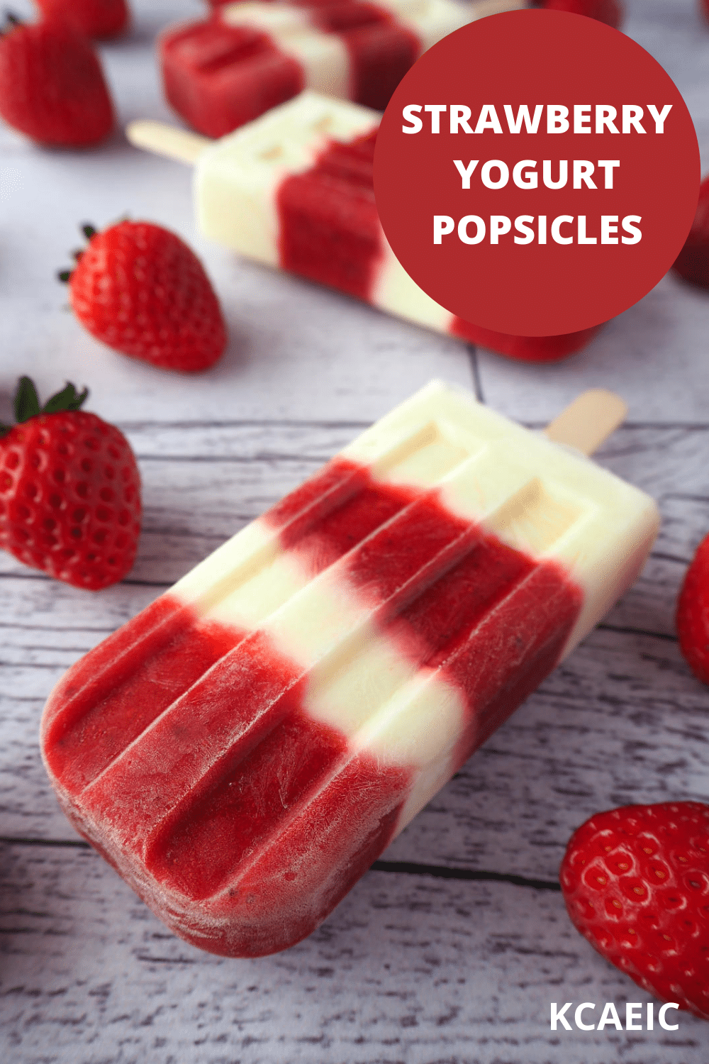 Strawberry yogurt popsicles 19 Close up strawberry yogurt popsicles on a diagonal surrounded by fresh strawberries with text overlay, strawberry yogurt popsicles, KCAEIC.