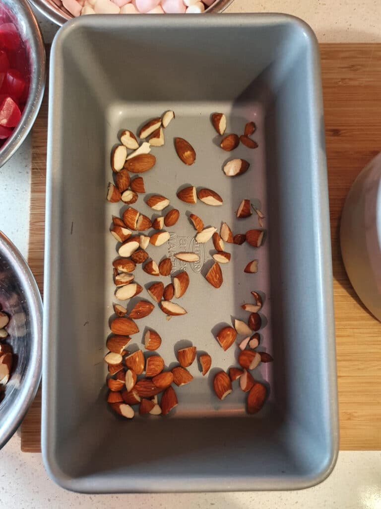 adding first layer of chopped almonds to bottom of chilled ice cream storage container.