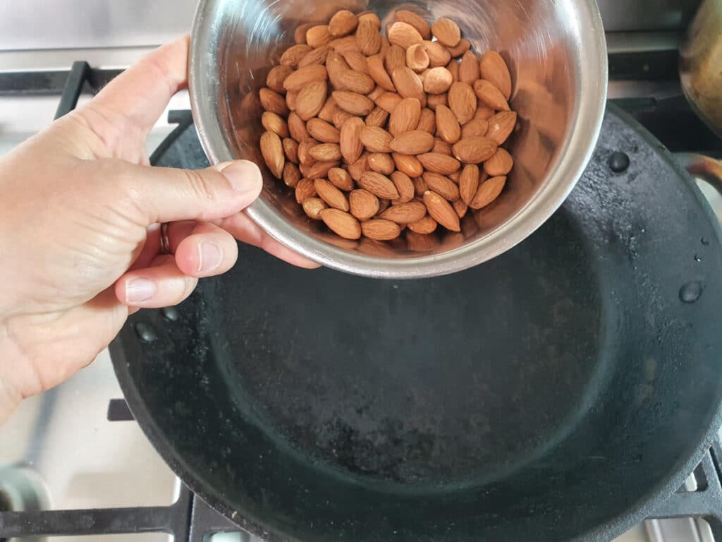 adding whole almonds to heated frying pan to dry roast.