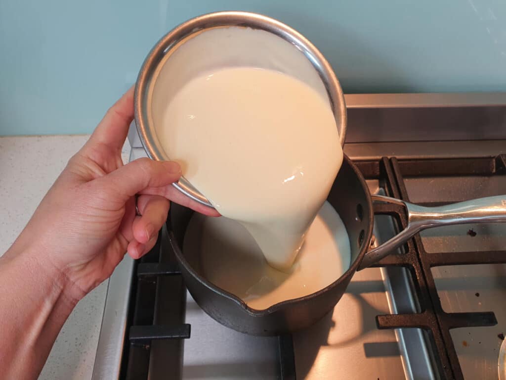 Milo ice cream 5 adding cream to ice cream mix in pot on stove.