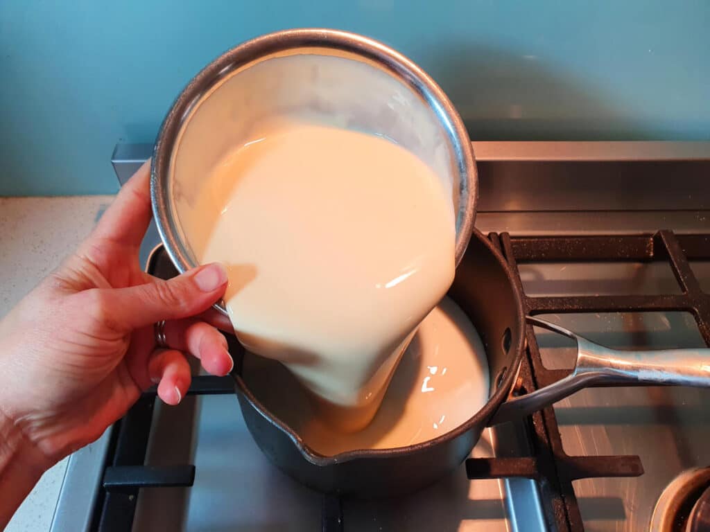adding cream to pot on stove.