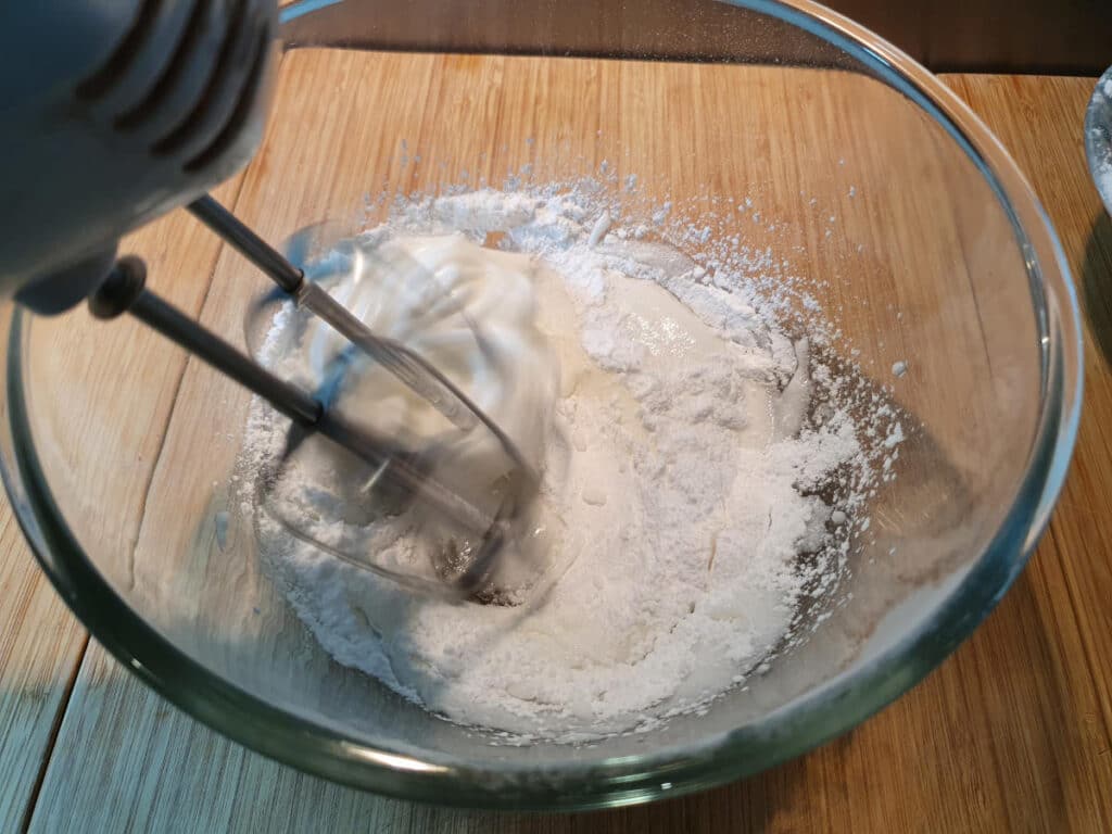 adding icing sugar to egg whites.