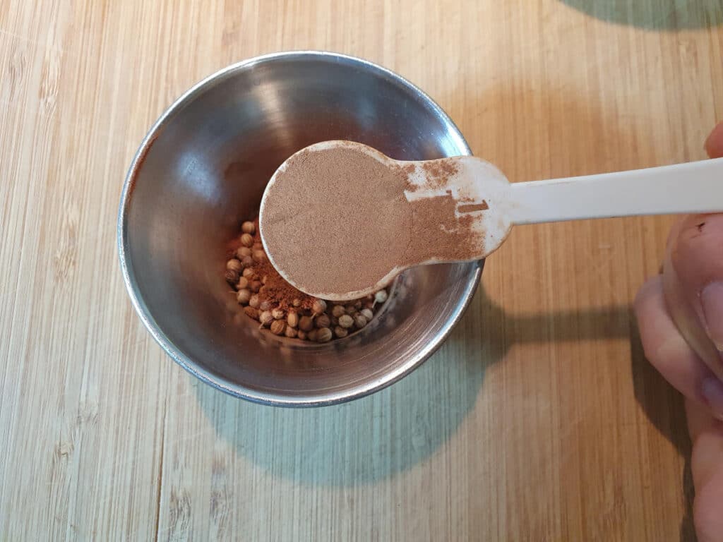 measuring kola nut power into a small metal bowl.