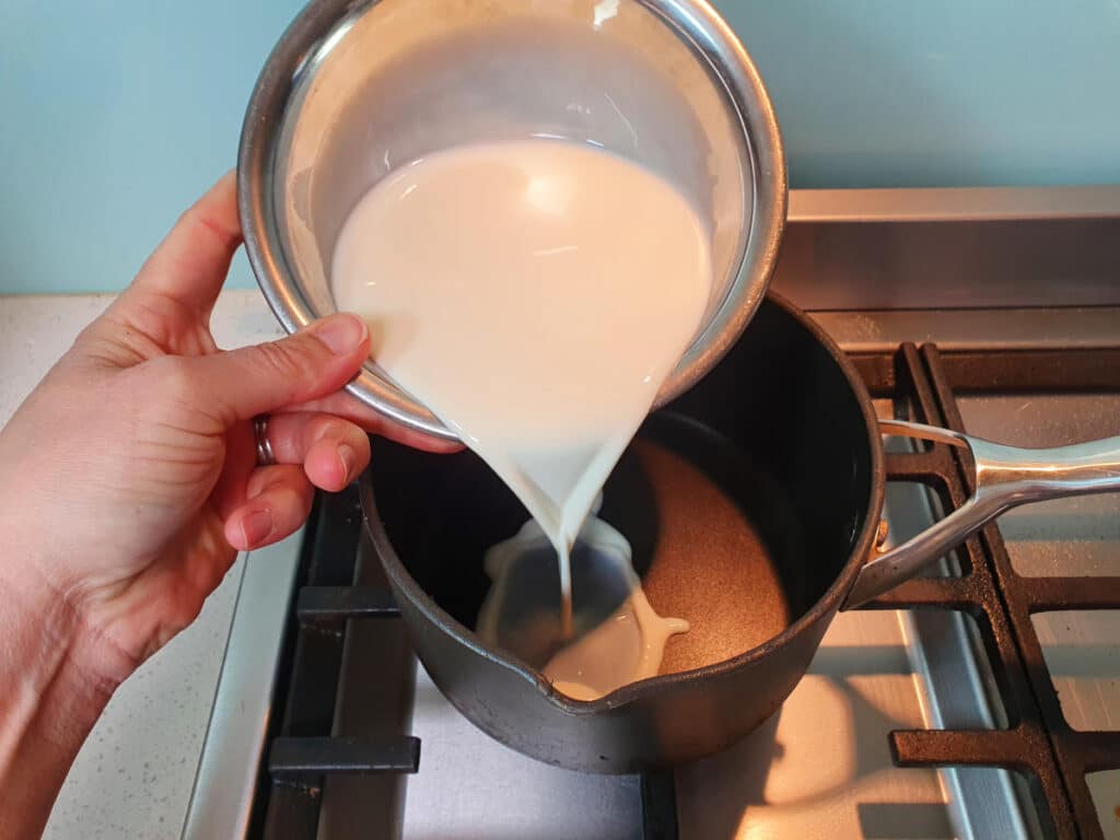 adding milk to ice cream mix in pot on stove.