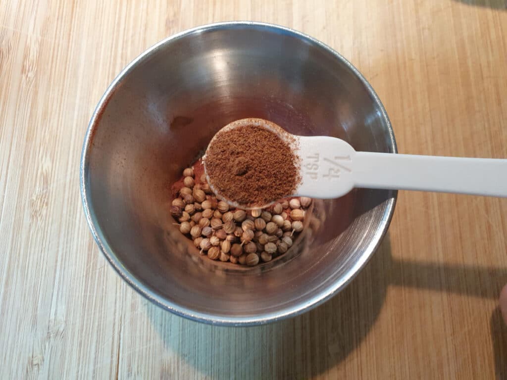 measuring nutmeg into a small metal bowl.