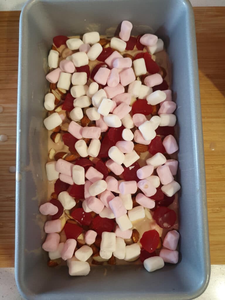 adding second layer of almonds, raspberries and marshmallows to ice cream.