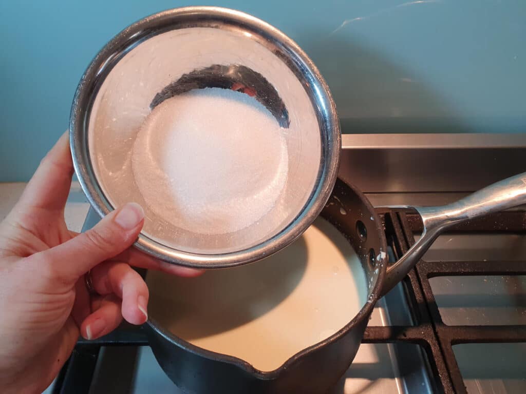 adding sugar to ice cream mix in pot on stove.