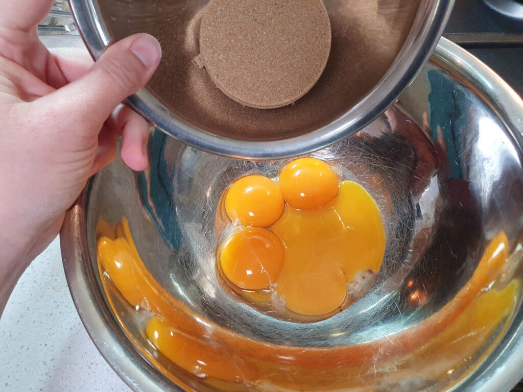 adding brown sugar to egg yokes.