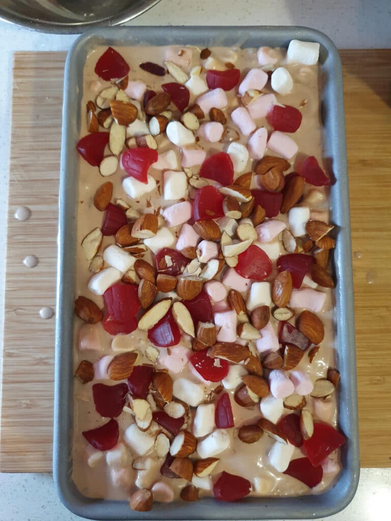 adding top layer of almonds, raspberries and marshmallows to ice cream.