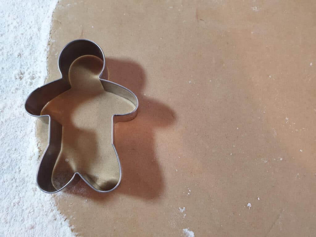 cutting gingerbread men shapes out of rolled out dough.