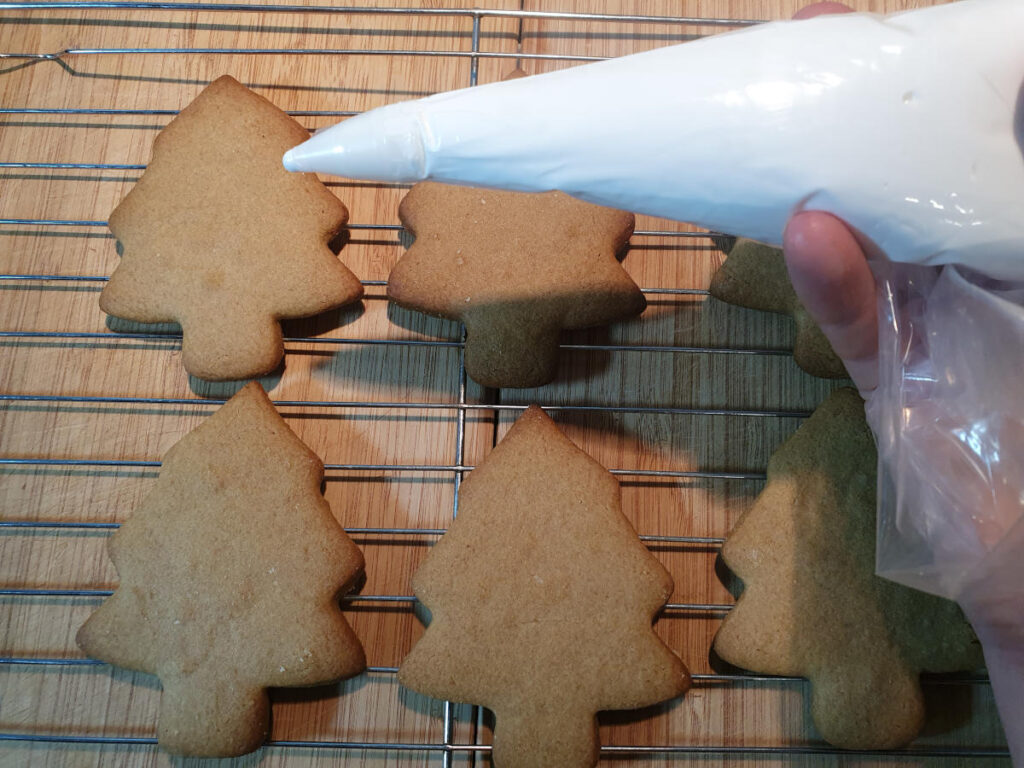 Gingerbread men 25 piping icing onto gingerbread trees to decorate.