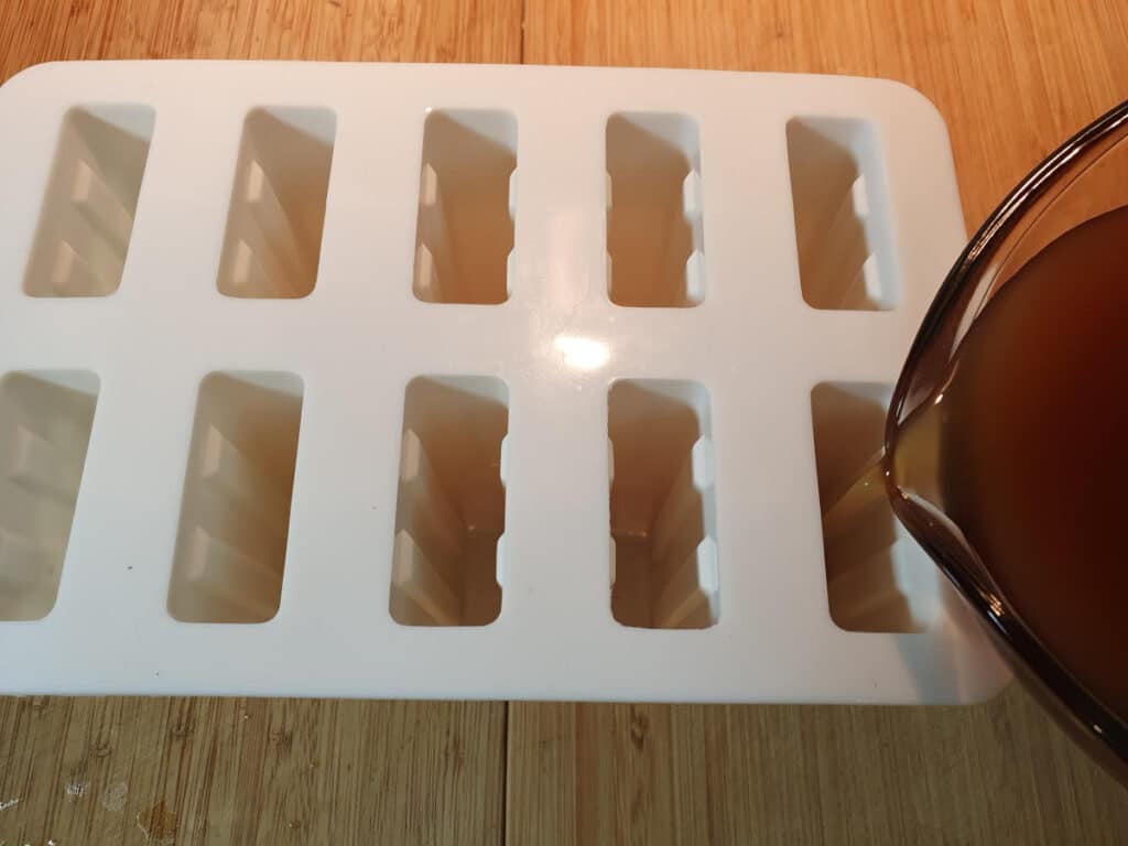 filling popsicle molds with cola mix.