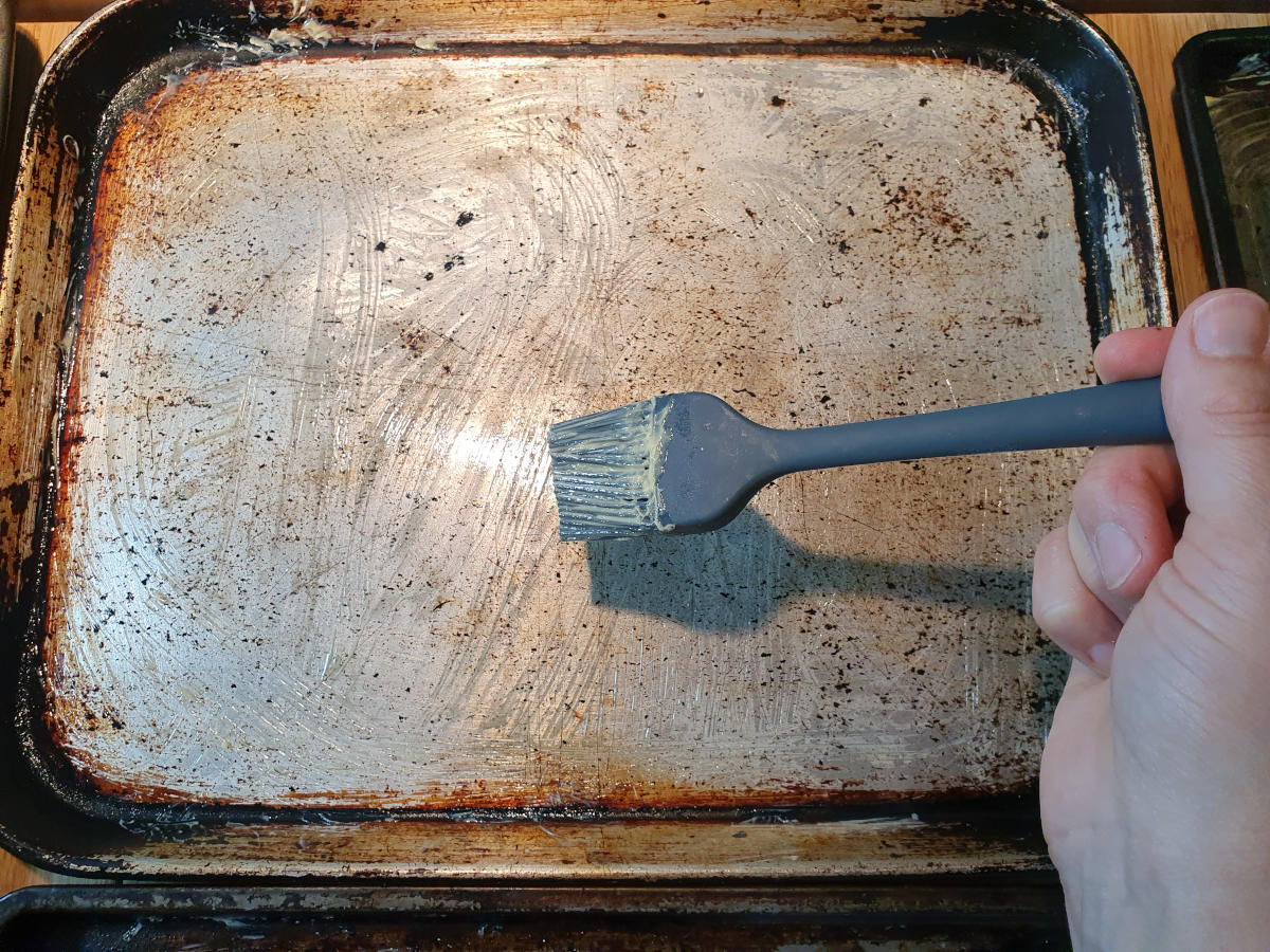 greasing trays with pastry brush and butter.