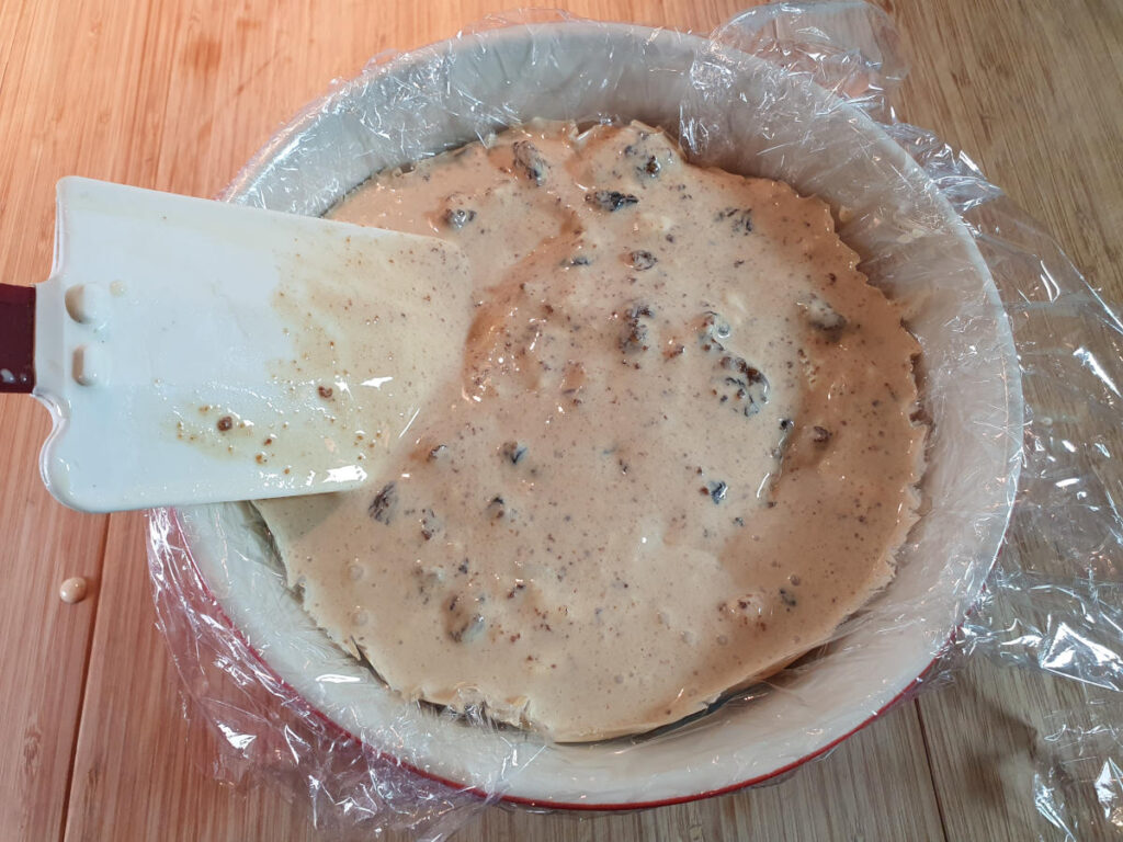 smoothing down pudding in pudding bowl with a spatula.