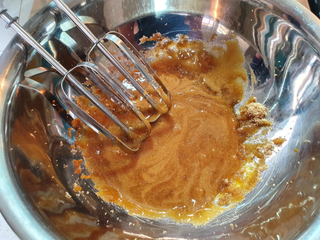 starting to blend egg yokes and brown sugar, showing dark color.