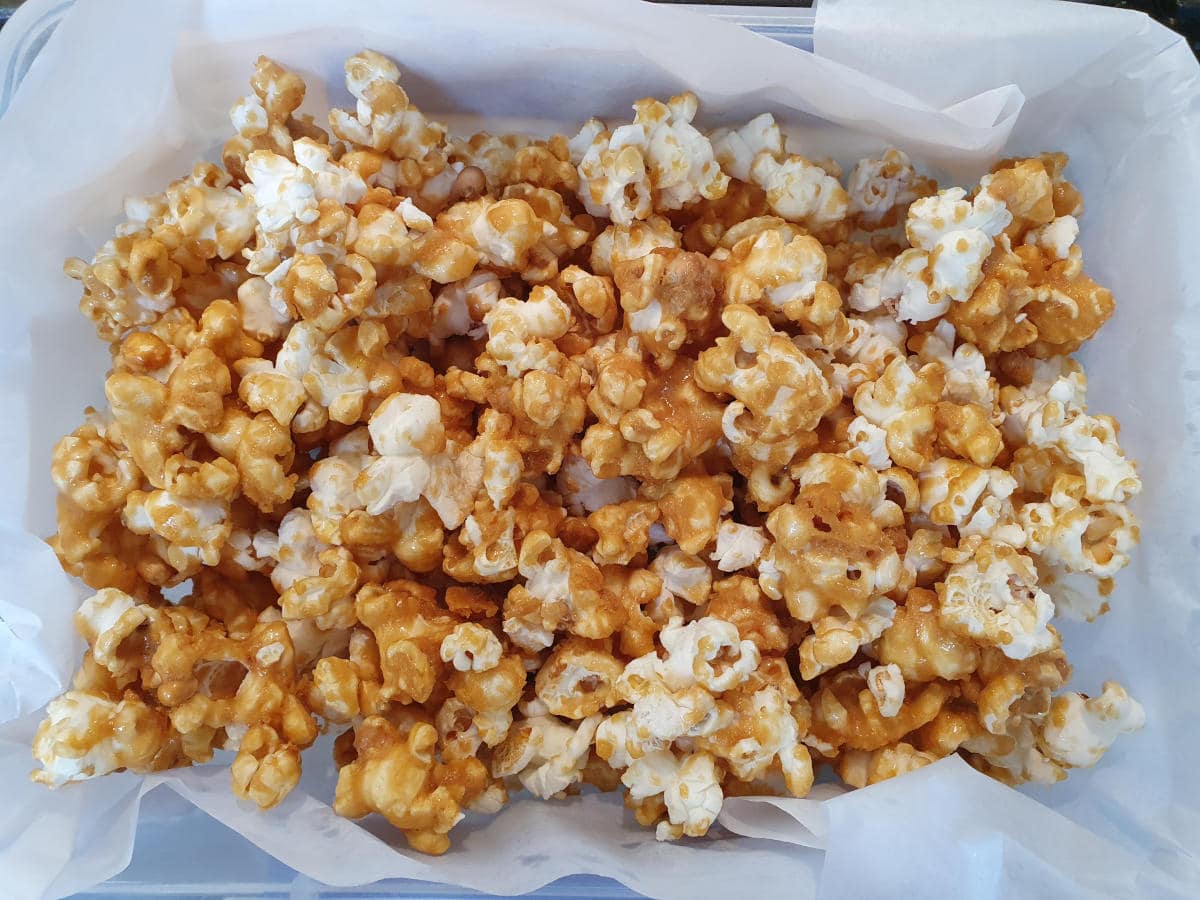 top down view showing popcorn being stores in airtight container lined with baking paper.