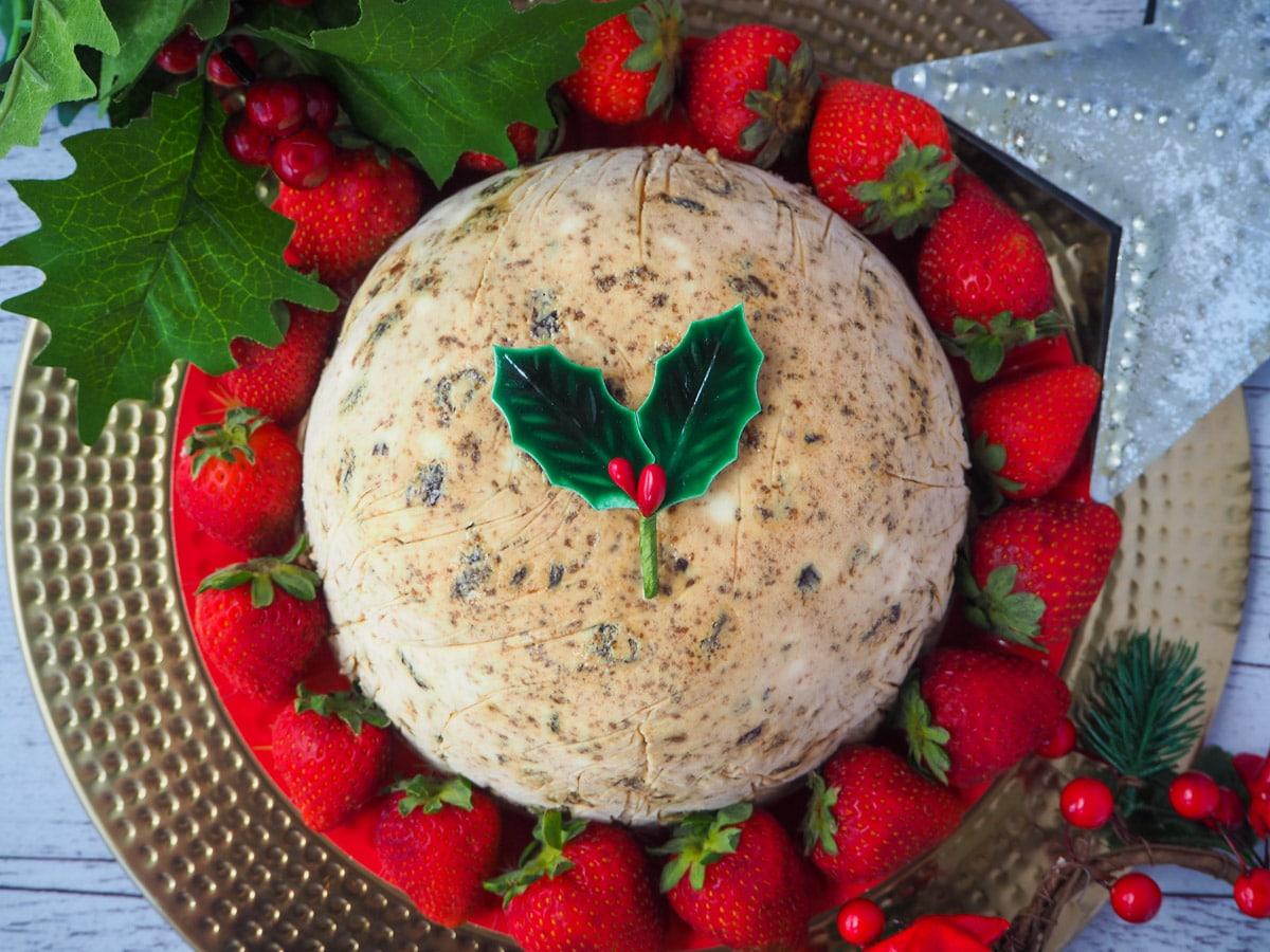 Top down view Christmas pudding ice cream with holly garnish, surrounded by fresh strawberries, with holly and a Christmas star in the at the side.