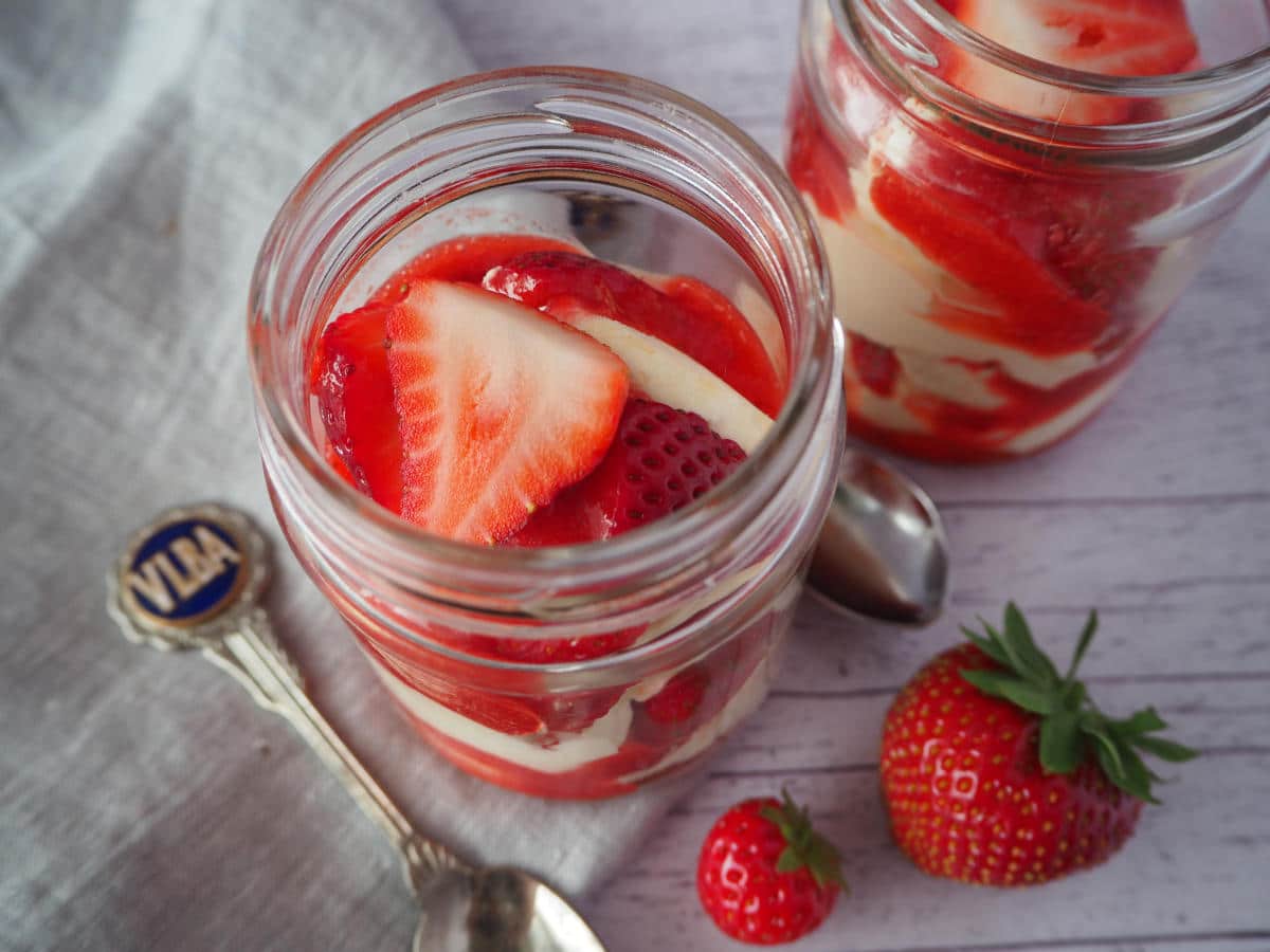 Eton mess 4 Two jars of Eton mess with fresh strawberries on the side, spoons and a linen cloth.