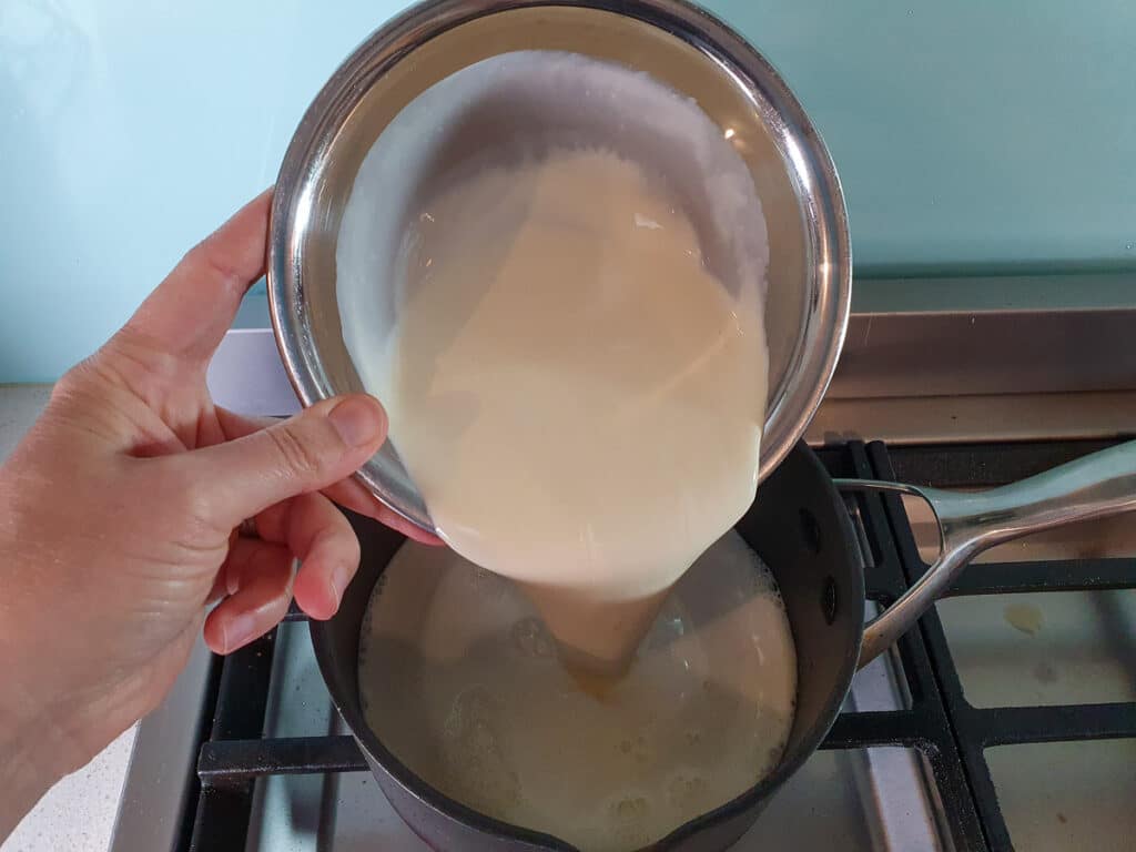 Mango ice cream 9 adding cream to pot on stove.