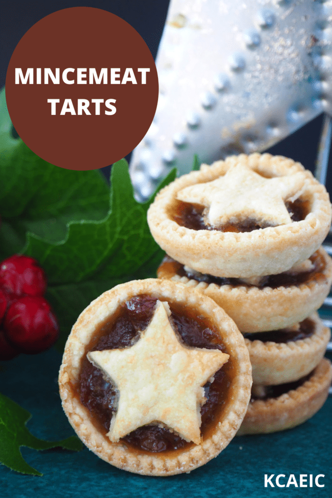 Mincemeat tart propped up against a stack of tarts, with holly and a star in the background and text overlay, mincemeat tarts and KCAEIC.