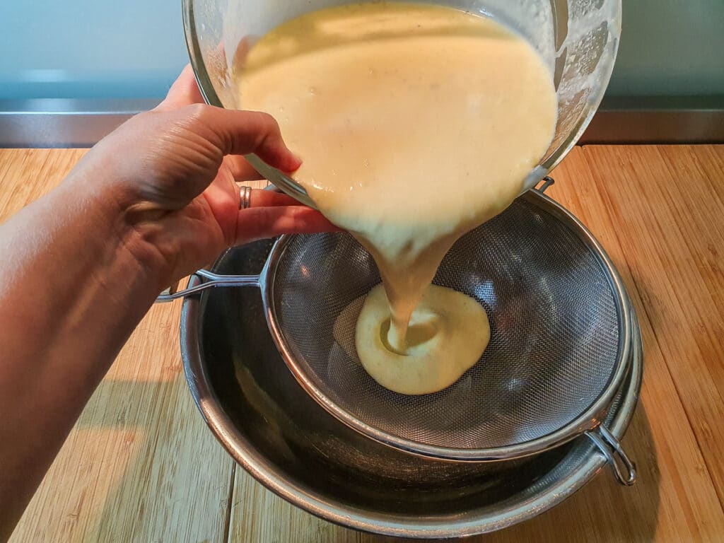 Pouring ice cream mix through sieve.
