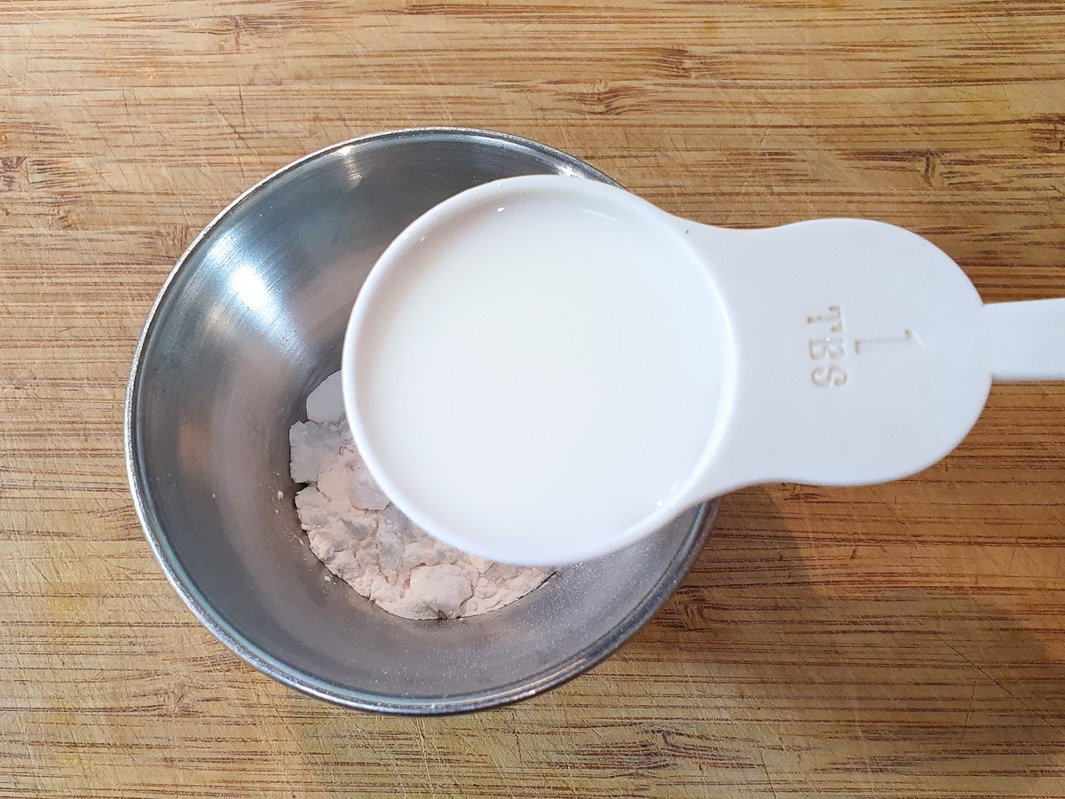 Adding milk to tapioca starch in a small bowl.