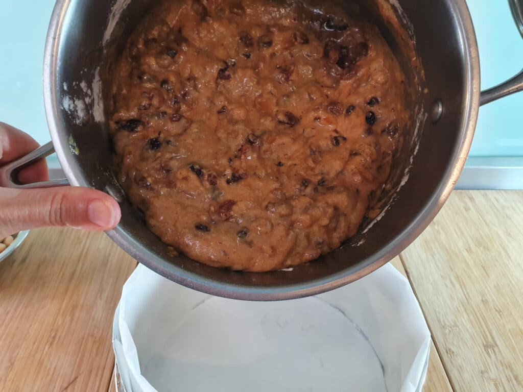 adding cake mix to lined cake tin.