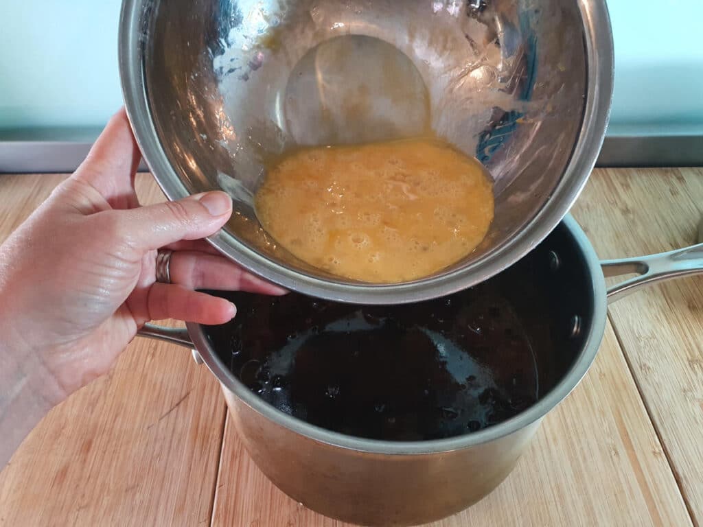 adding egg and brandy mix to cooled cake mix in pot.