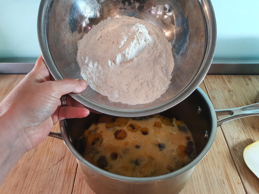 adding flour to cake mix in pot.