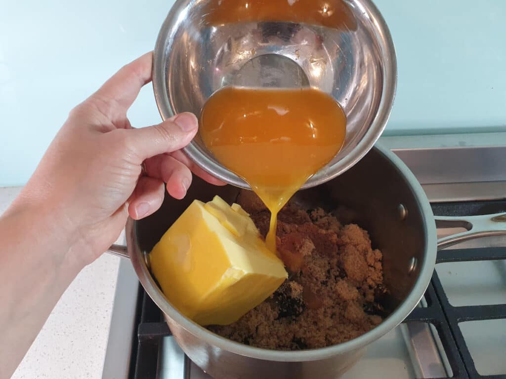 adding orange juice to pot on stove.