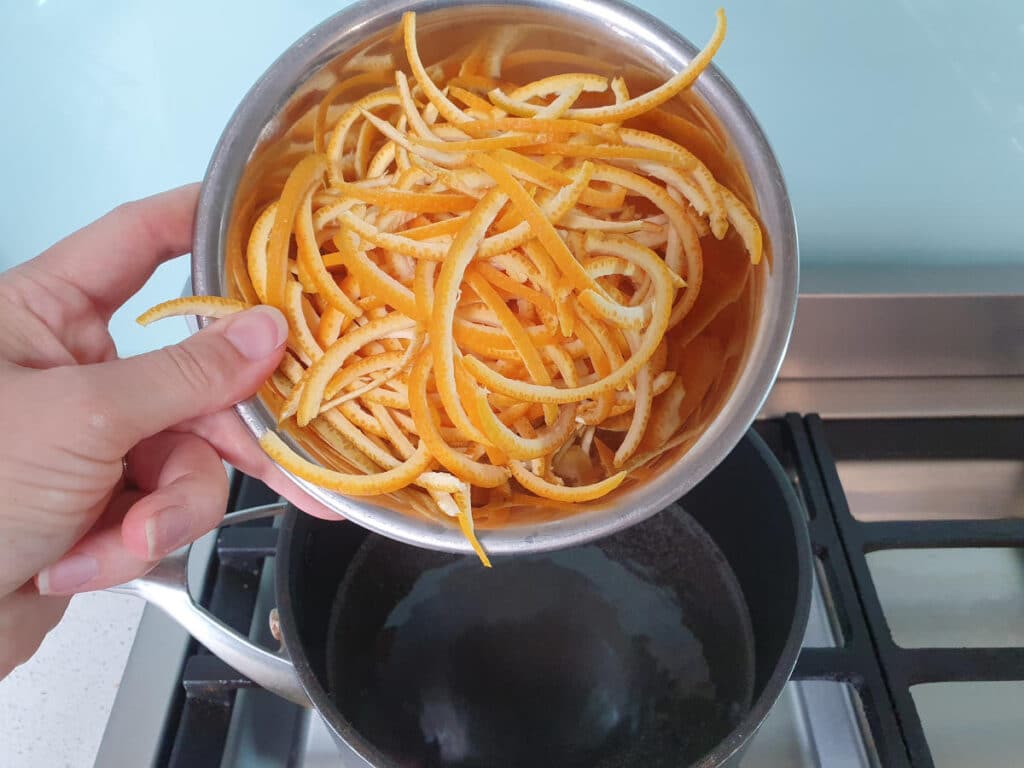 adding peel to sugar syrup to pot on stove.