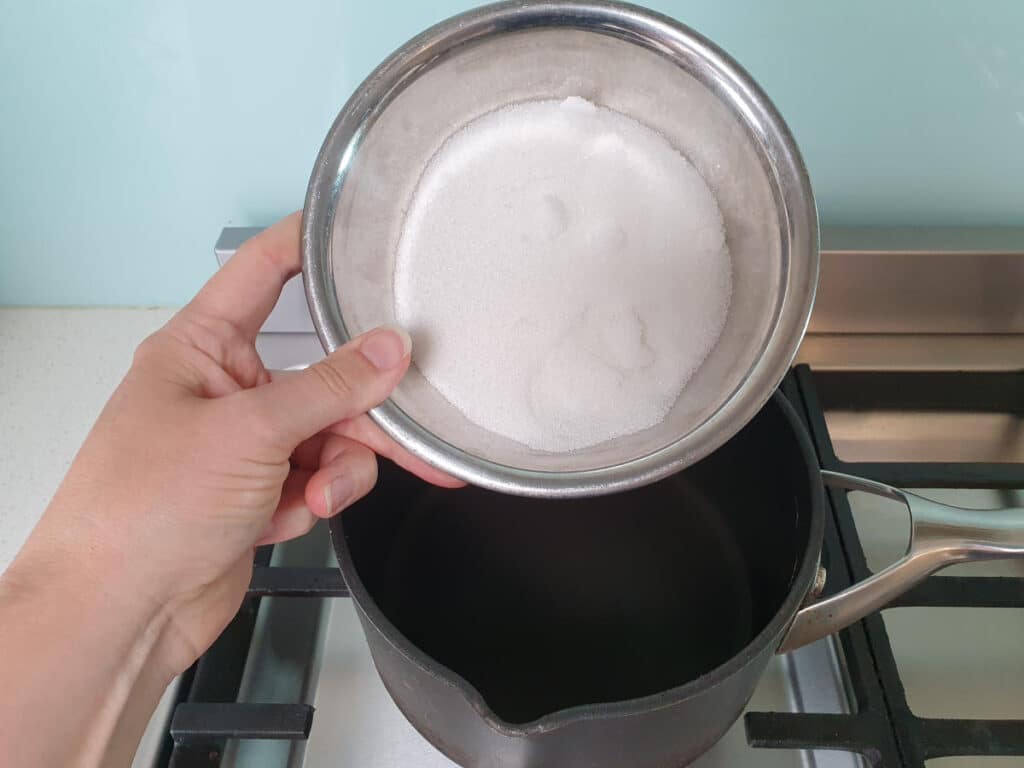 adding sugar to pot on stove.