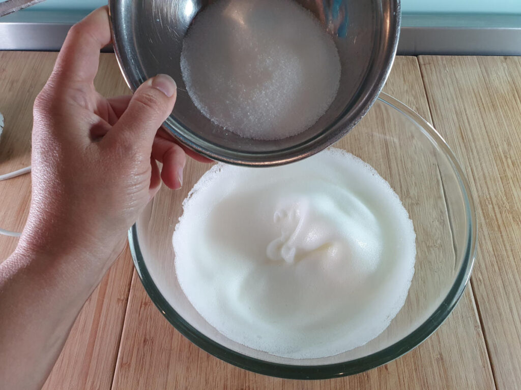 adding sugar to whipped egg whites.