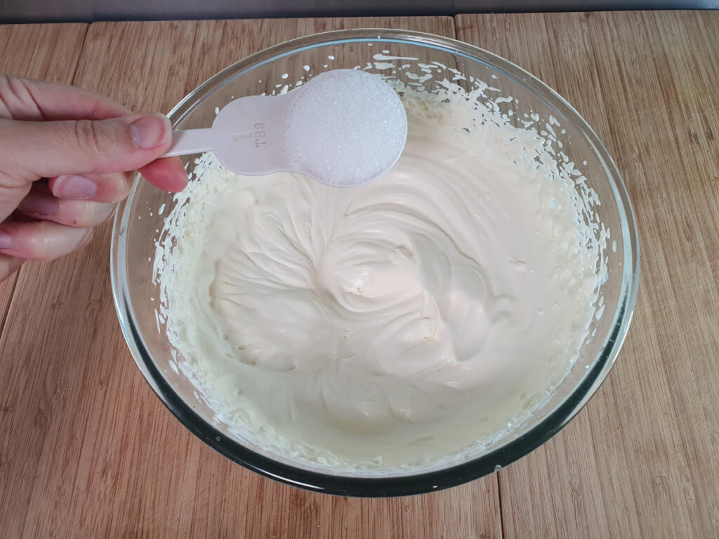 adding sugar to whipped cream.