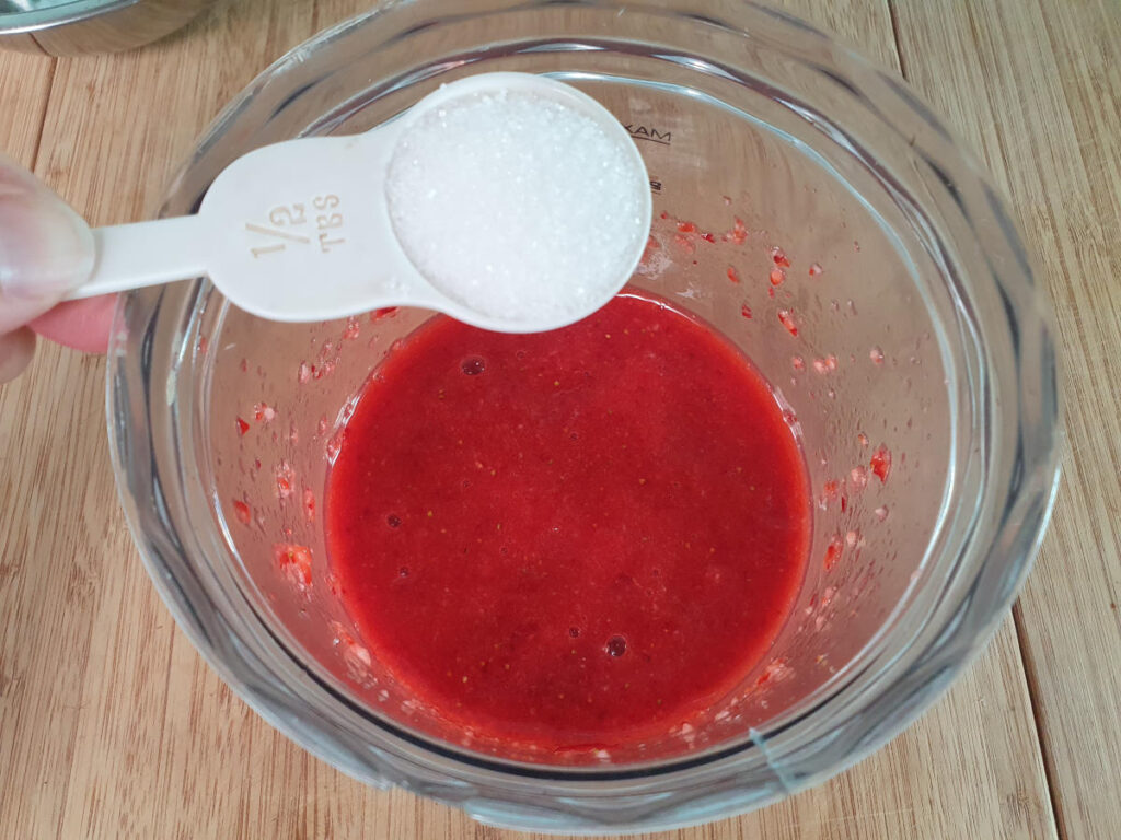 adding sugar to strawberry sauce in food processor.