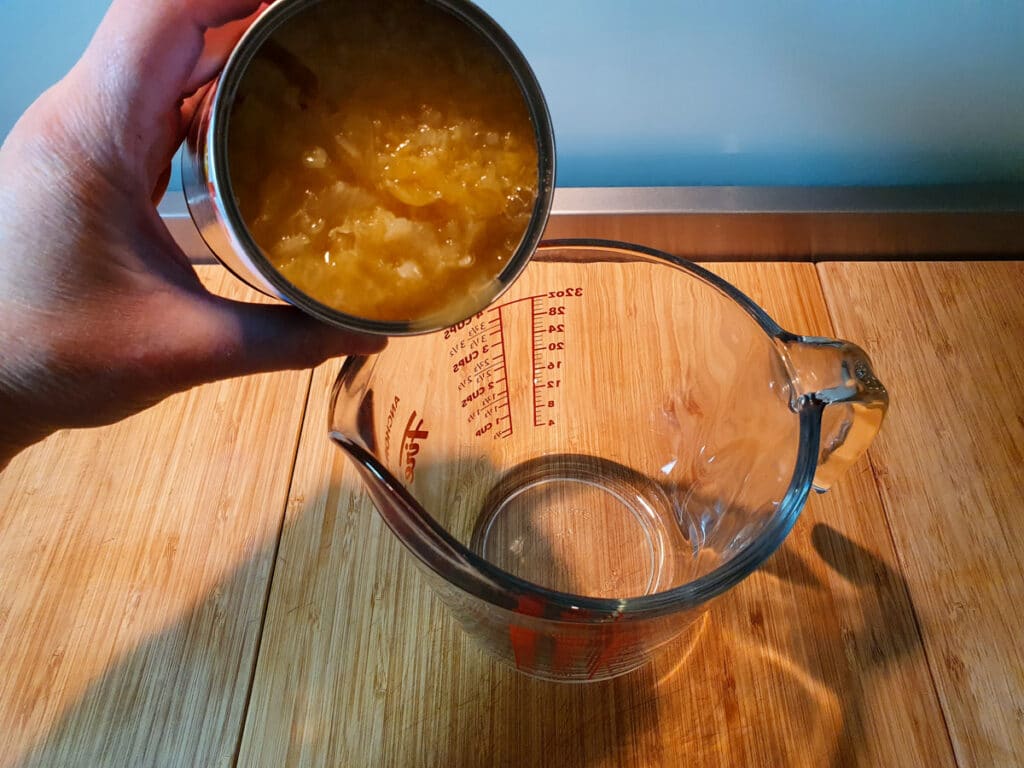 adding tinned pineapple to jug.